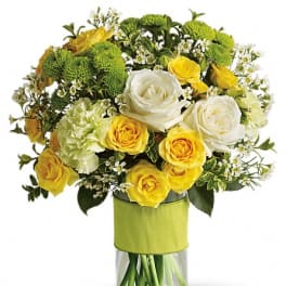 Yellow and white roses with green pompons in a glass vase