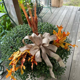 Round fall planter with a burlap bow and orange leaf accents