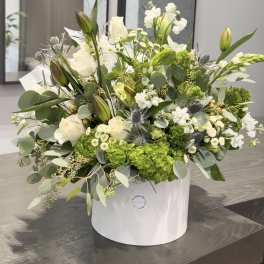 White and green floral arrangement in a white hat box