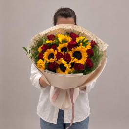 Large bouquet of sunflowers and red roses wrapped in beige paper