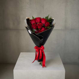 Bouquet of red roses wrapped in black paper with a red ribbon