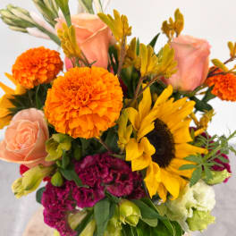 Bouquet with peach roses, orange marigolds, yellow sunflower, and magenta blooms
