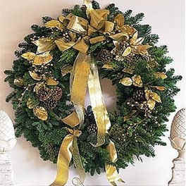 Evergreen wreath with gold ribbon, pinecones, and gold accents hanging above a mantel.