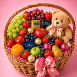 Gift basket with fruit, chocolates, and a teddy bear in a wicker basket