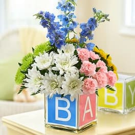 Colorful flower arrangement in alphabet blocks with blue, white, pink, and yellow blooms