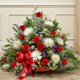 Large basket arrangement with red roses, white spider mums, and a red ribbon