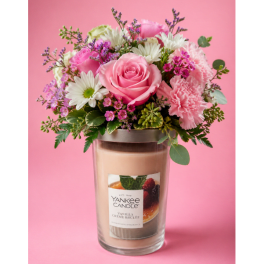 Pink and white flower arrangement in a glass candle jar