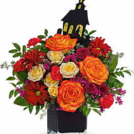 Halloween bouquet with orange and red roses in a black vase with a haunted house pick