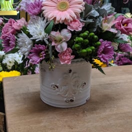 Pink and white mixed flower arrangement in a white ceramic container