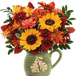 Autumn bouquet of sunflowers and chrysanthemums in a green ceramic pitcher