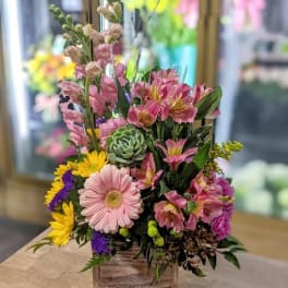 Mixed floral arrangement in a wooden box with pink and yellow blooms