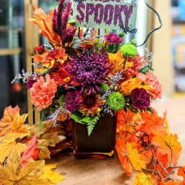 Halloween floral arrangement in a vase with a "Filling Spoon" sign