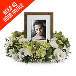 White and green sympathy frame surrounded by flowers