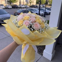 Bouquet of pale pink and yellow roses wrapped in yellow paper