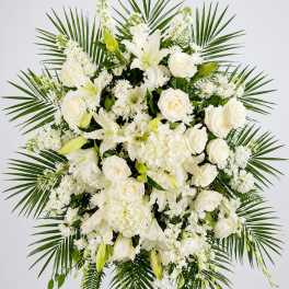 White floral standing spray with roses, lilies, and palm fronds
