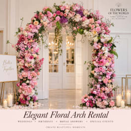 Pink and white floral arch framing a doorway with candles nearby
