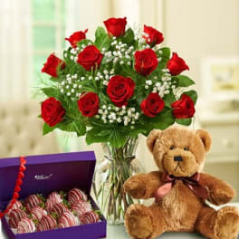 Red rose bouquet in a glass vase with a teddy bear and box of chocolate-covered strawberries