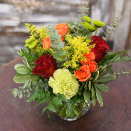 Bouquet of red and orange roses with yellow flowers in a glass vase