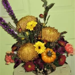 Autumn floral arrangement with yellow blooms and a small pumpkin