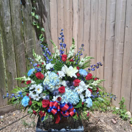 Large mixed flower arrangement in a basket with red, blue, and white blooms