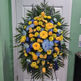 Large standing spray of yellow, blue, and orange flowers on a stand