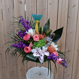 Tropical floral arrangement in a clear pedestal vase with purple and pink blooms