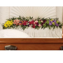 Colorful floral spray arranged across a casket lid