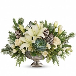 Low centerpiece of white lilies and roses with succulents, pinecones, and evergreens in a silver pedestal bowl