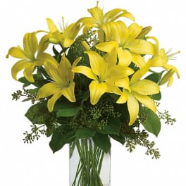 Arrangement of yellow lilies in a tall clear glass rectangular vase