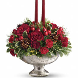 Low red rose and carnation centerpiece with two tall red candles in a silver pedestal bowl
