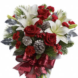 Holiday bouquet of red roses, white lilies, red carnations, pinecones and berries in a glass vase