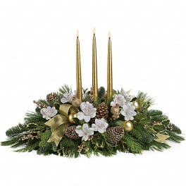 Evergreen holiday centerpiece with white flowers, pinecones, and three tall gold taper candles