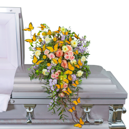 Casket spray with pink and cream roses, lavender flowers, and orange butterflies
