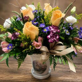Mixed bouquet of roses, daisies, and carnations in a frosted vase with ribbon