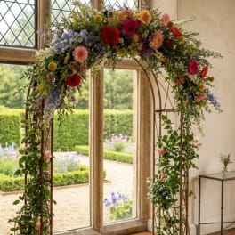 Colorful floral arch with mixed blooms and trailing greenery