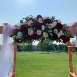 Floral arch arrangement with pink, white, and burgundy flowers
