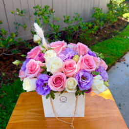 Pink and white roses with purple blooms in a white box