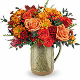 Bouquet of orange and red flowers in a rustic ceramic pitcher