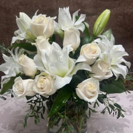 White roses and lilies arranged in a glass vase