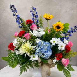 Mixed bouquet in a white vase with roses, daisies, hydrangea, and sunflowers
