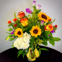 Mixed bouquet with sunflowers, roses, and white hydrangea in a glass vase