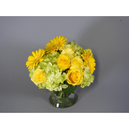 Yellow roses and gerbera daisies in a glass vase
