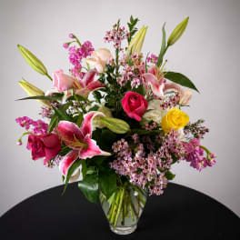 Mixed bouquet of pink lilies and roses in a clear glass vase