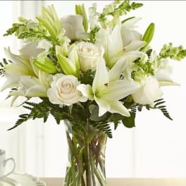 White lilies and roses arranged in a clear glass vase