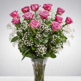 Pink roses arranged in a clear glass vase with small white filler flowers