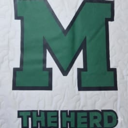 Green letter M with the words THE HERD on a white quilted background