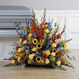 Large funeral spray with sunflowers, yellow roses, and red flowers in a basket base