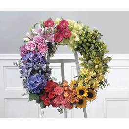 Colorful floral wreath on a stand with roses, lilies, hydrangeas, and sunflowers