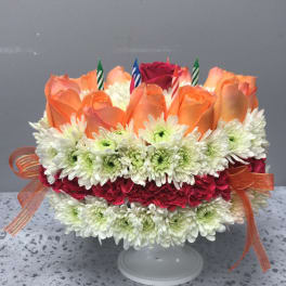 Orange roses and white daisies arranged on a cake stand with candles
