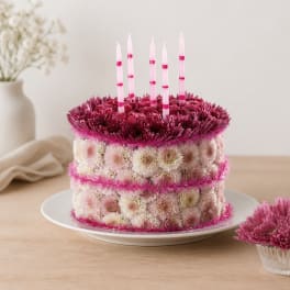 Flower-covered cake with pink candles on a white plate